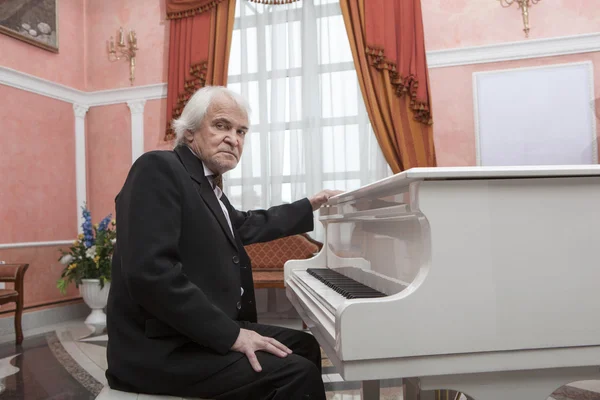 Musicista maturo che suona un pianoforte bianco — Foto Stock