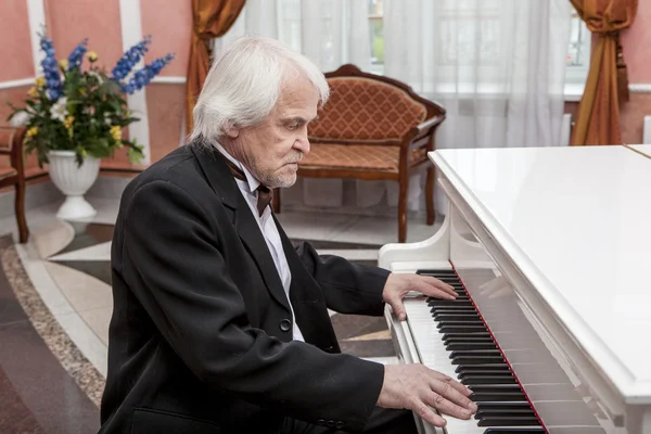 Volwassen muzikant een witte piano spelen — Stockfoto