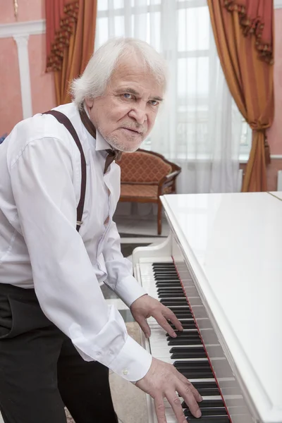 Mature musician playing a white piano — Stock Photo, Image