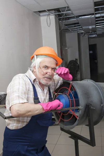 Чоловік ремонтує промисловий обігрівач — стокове фото