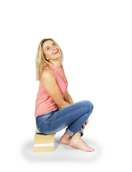 Young woman sitting on a pile of books — Stock Photo, Image