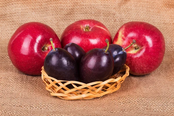 Three red apples and four plums — Stock Photo, Image