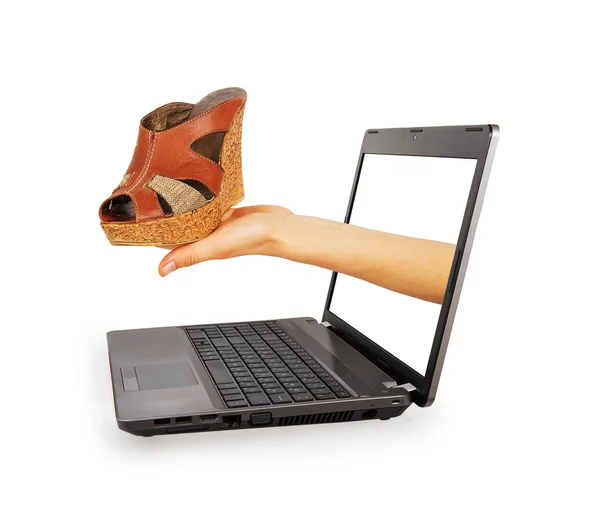 Hand eines Laptops streckt weibliche Sandalen — Stockfoto