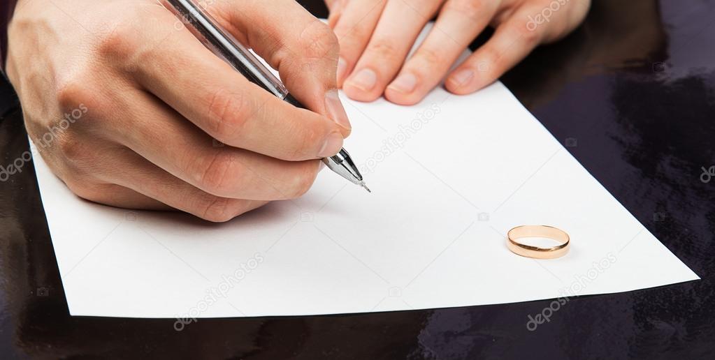 Closeup of male hand signing divorce papers 