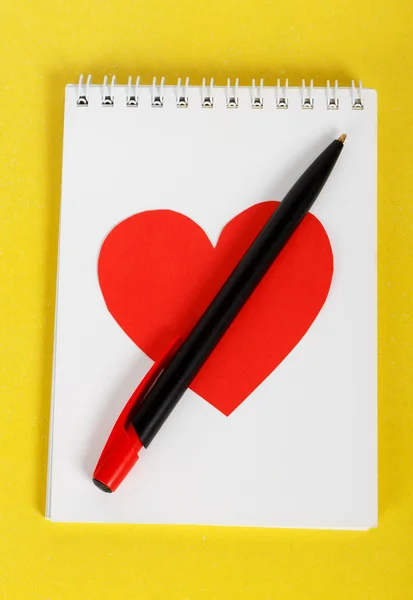 Červené srdce s černým perem na bílý notebook — Stock fotografie