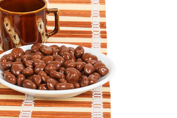 Chocolade dragees in een witte schotel op een bamboe-mat — Stockfoto