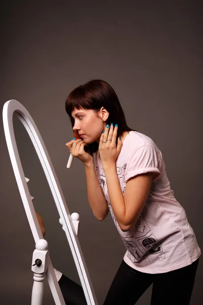 Mujer joven aplica maquillaje delante de un espejo grande —  Fotos de Stock