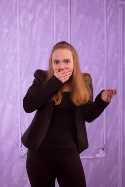 Siyah elbiseli bir genç kadın eliyle ağzını kapalı