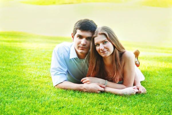 Casal deitado na grama verde — Fotografia de Stock