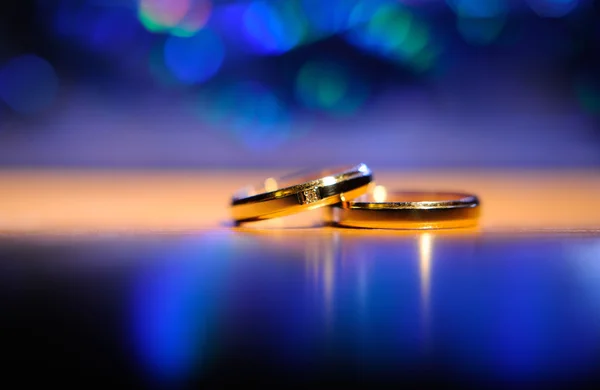 Par de anillos de boda de oro sobre fondo bokeh —  Fotos de Stock