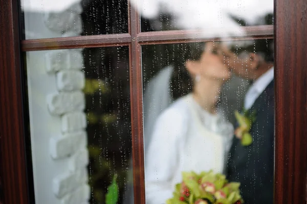 빗방울과 창 뒤에 키스 하는 신혼 부부 — 스톡 사진
