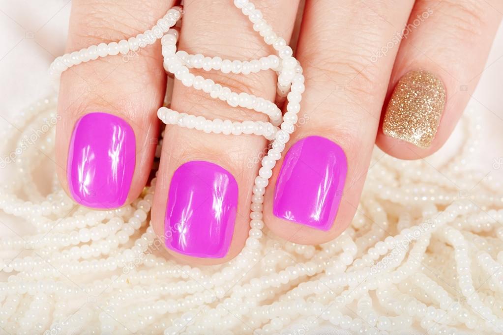 Manicured nails covered with pink nail polish and pearl necklaces