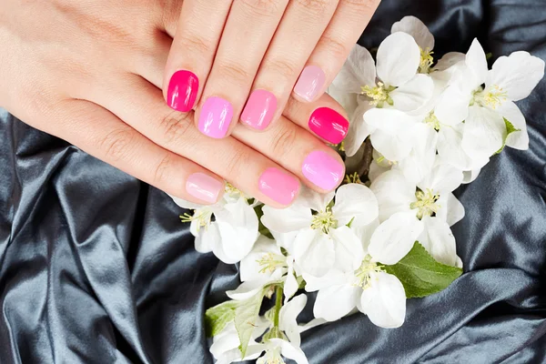 Hands with manicured nails on flowers background