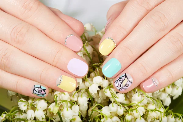 Manos con hermosas uñas cuidadas y lirio de las flores del valle — Foto de Stock