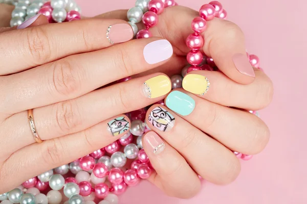Ruce s krásné pěstěné nehty drží barevné náhrdelníky — Stock fotografie
