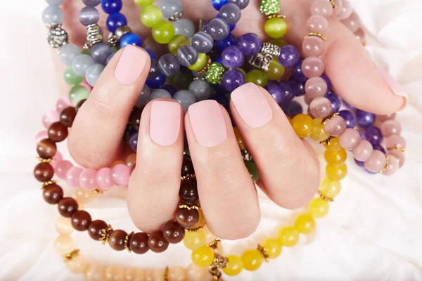 Mano con unghie curate opache beige e bracciali colorati — Foto Stock