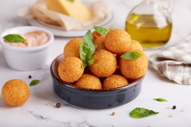 Kızarmış peynir topları. Lezzetli ev yapımı aperatif. Taze pişmiş kroket, fesleğen yaprakları ve sos ile servis edilir..