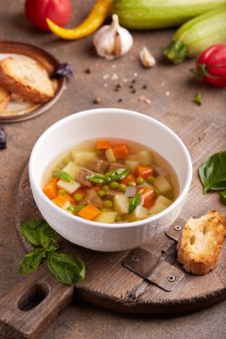 Et suyu, bezelye, kabak, patates ve havuç. Lezzetli ev yapımı temiz çorba, fesleğen yaprağı ve tost ile servis edilir..