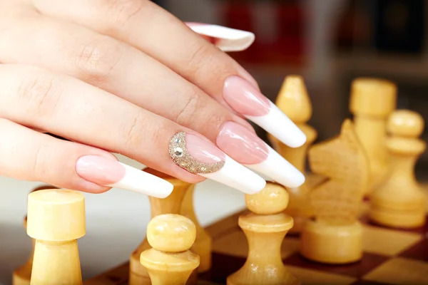 Hand with french manicure playing chess — ストック写真
