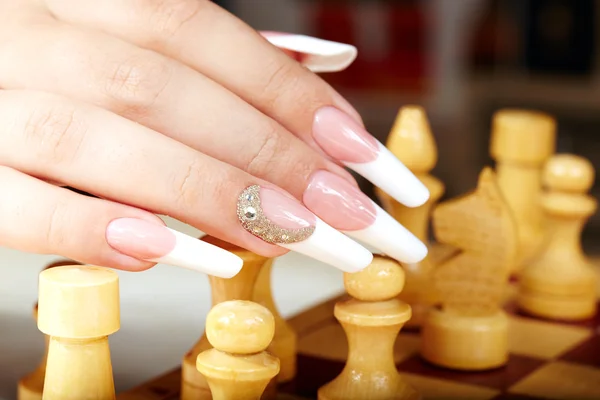 Hand with french manicure playing chess