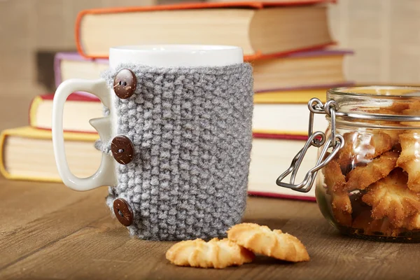 Чашка чая с вязаной крышкой и печеньем — стоковое фото