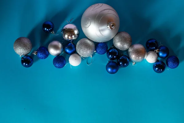 Сияющие рождественские шары в голубом, белом и серебристом цветах расположены в ряд на бирюзовом фоне с пробелами для текста. — стоковое фото