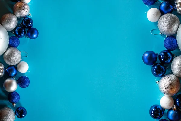 Блискучі різдвяні кульки в синьому, білому і срібному кольорах розташовані в рядку на бірюзовому фоні з пробілом для тексту . — стокове фото