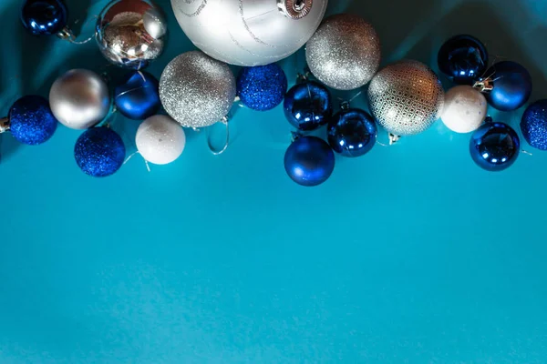 Mavi, beyaz ve gümüş renkli parlak Noel topları, metin için bir boşluk ile turkuaz arka planda sıralanır. — Stok fotoğraf