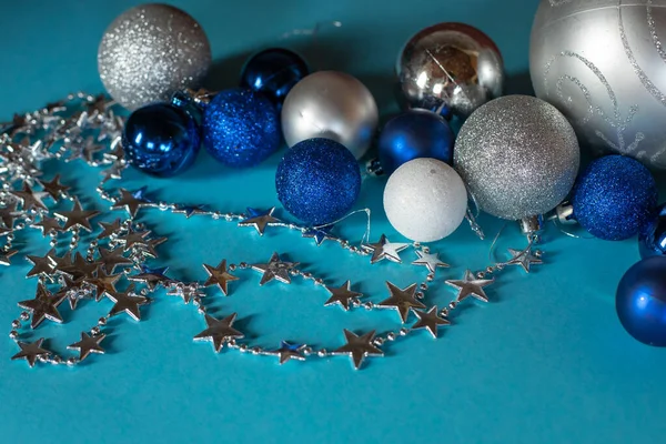 Noel süslemeleri. Bir yıldız çelengi ve turkuaz arka planda farklı boyutlarda parlak Noel topları.. — Stok fotoğraf