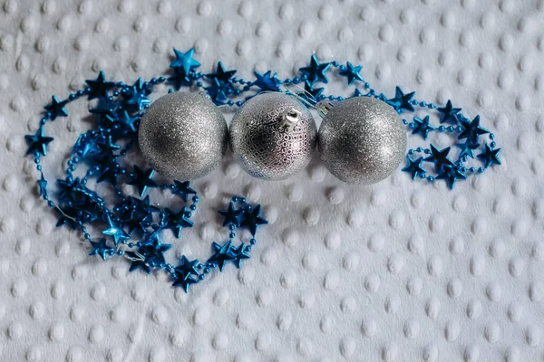 Beyaz arka planda üç parlak gümüş Noel topu sıraya dizilir ve mesaj için bir boşluk oluşturulur..