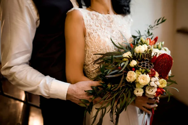 新郎和新娘手里拿着一束鲜花和绿叶拥抱着 — 图库照片