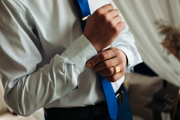 stock image A sexy male businessman fastens a cufflink on his wrist watch, the cuff of the sleeve of a luxurious white shirt. Tonal correction