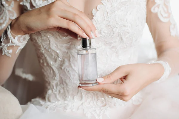 jar of perfume in the hands of the bride. Beautiful wedding manicure.Hands closeup. Wedding morning bride