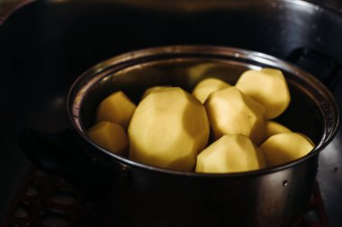Gümüş bir tencerede soyulmuş patates. Pişirmek için temiz patates. Koyu arkaplanda patates soyulmuş tabaklar. Bir damla su