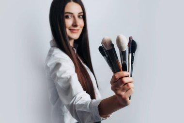 Makyaj sanatçısının fırçaları ön planda. Aydınlık bir arkaplanda, izole