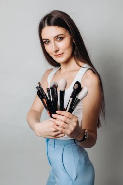 Makyaj sanatçısının fırçaları ön planda. Aydınlık bir arkaplanda, izole