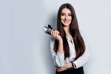 Beyaz arka planda elinde fırçayla makyaj sanatçısı.