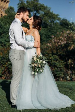 Eyfel Kulesi 'nin arka planında birbirine aşık yeni evliler. Mavi elbiseli, düğün buketli bir kız. Mavi elbiseli, düğün buketli bir kız.