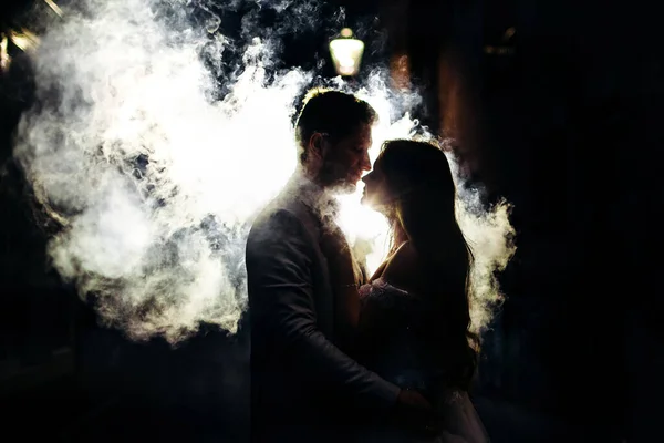 Sokakta dumanlı bir arka planda öpüşen adam ve kadın. Gece vakti Weddind şehirde