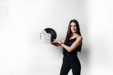 Plağı olan genç bir kız. Siyah elbiseli bir kızın elinde, açık renk arka planda bir plak plağı. Metin için boşluk