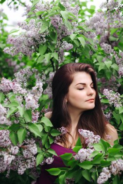 Leylak bahçesinde güzel bir kız. Baharda leylak çiçekli bir kız. Bahçıvanlık.