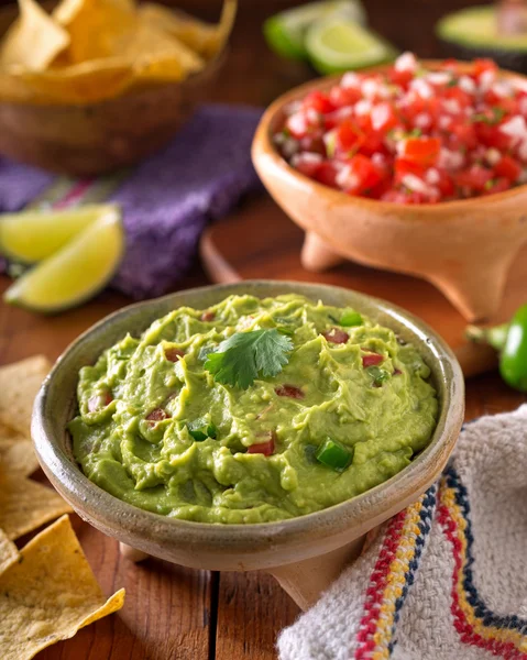 A delicious authentic mexican guacamole dip with avacado, lime, tomato, cilantro, and jalapeno pepper. — Stock fotografie