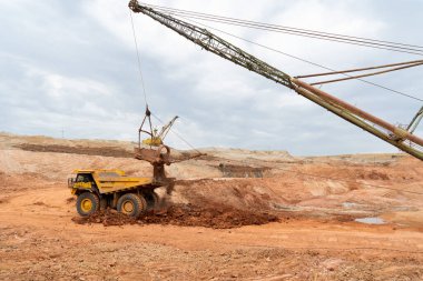 Büyük kazıcı kayaları demir ya da boksit ile doldurur. Bir taş ocağında gökyüzüne karşı dökülür.