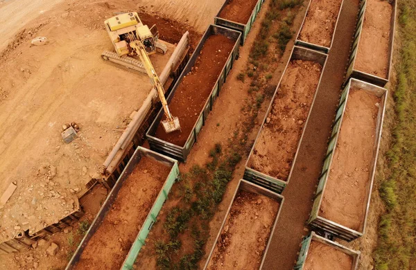 large excavator loads rock with iron or bauxite mining dump truck in a quarry against the sky