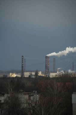 Bir sanayi bölgesinin kentsel manzarası, dumanın yayıldığı yüksek bacalar