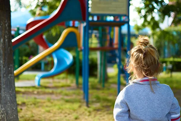 Petite fille mignonne regardant avec son dos tourné sur le terrain de jeu dans le parc — Photo