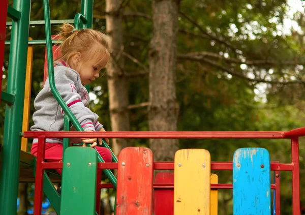 Le petit tout-petit mignon va sur les marches de l'aire de jeux dans le parc — Photo