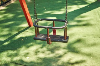 Yeşil halılı çocuk parkında boş salıncaklar 