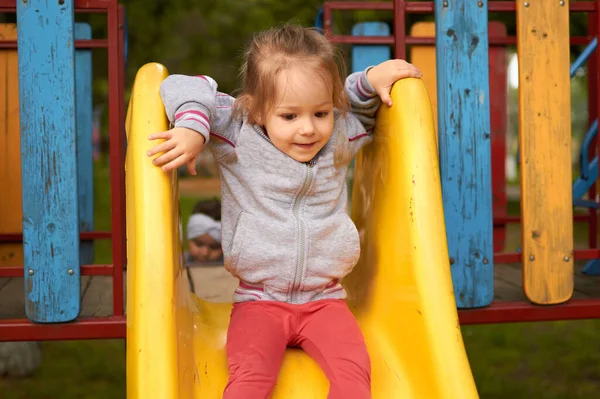 Petite fille mignonne préscolaire glisse sur l'aire de jeux dans le parc — Photo