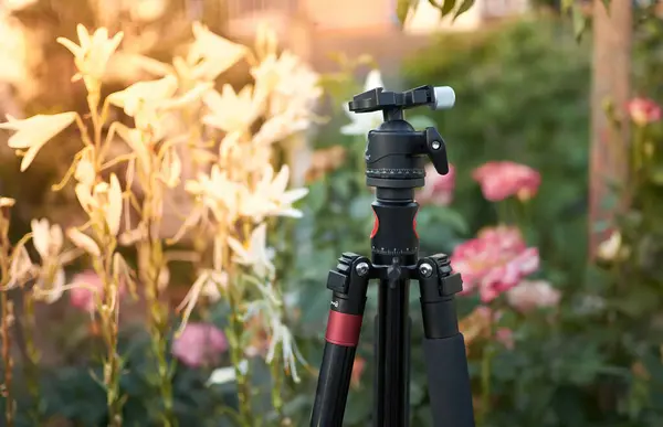 Close up of black tripod without camera flower background — Stock Photo, Image